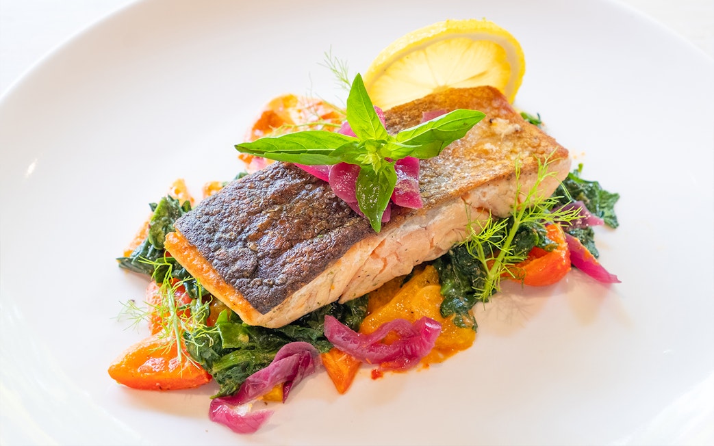 Grilled salmon with vegetables and lemon garnish served at Dinner in the Sky.