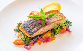 Grilled salmon with vegetables and lemon garnish served at Dinner in the Sky.