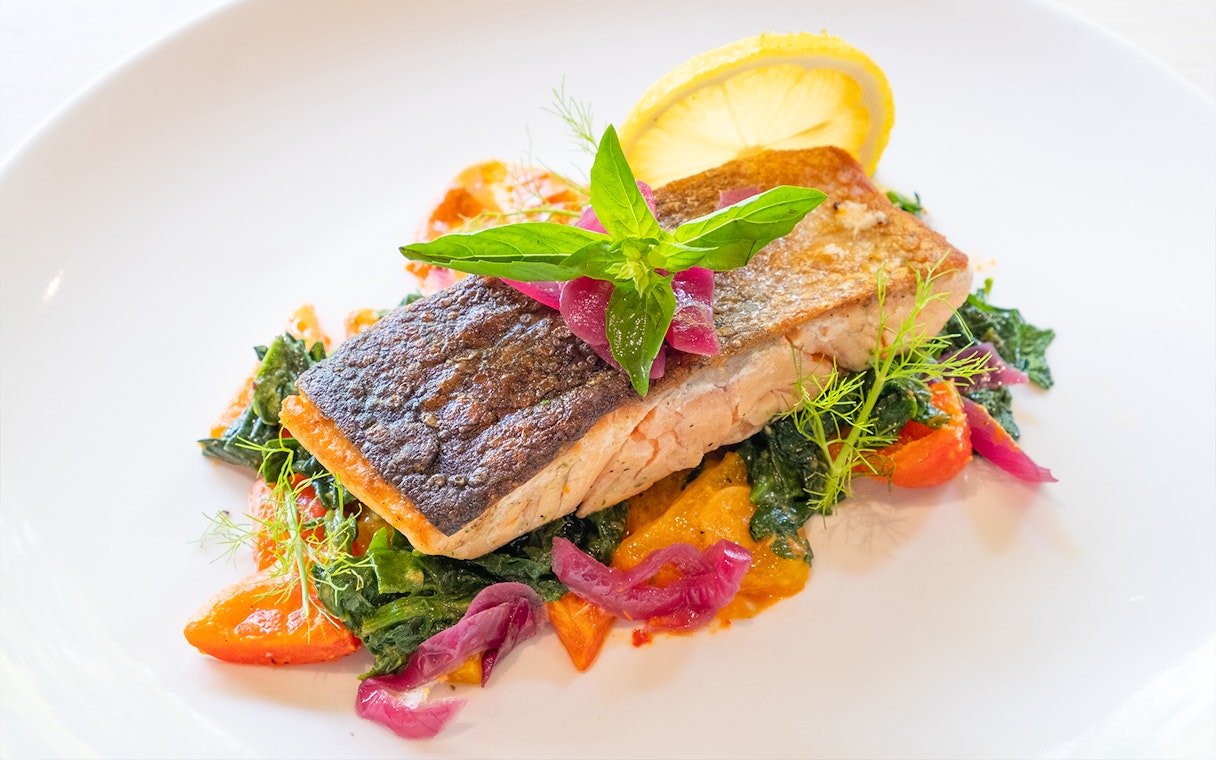 Grilled salmon with vegetables and lemon garnish served at Dinner in the Sky.