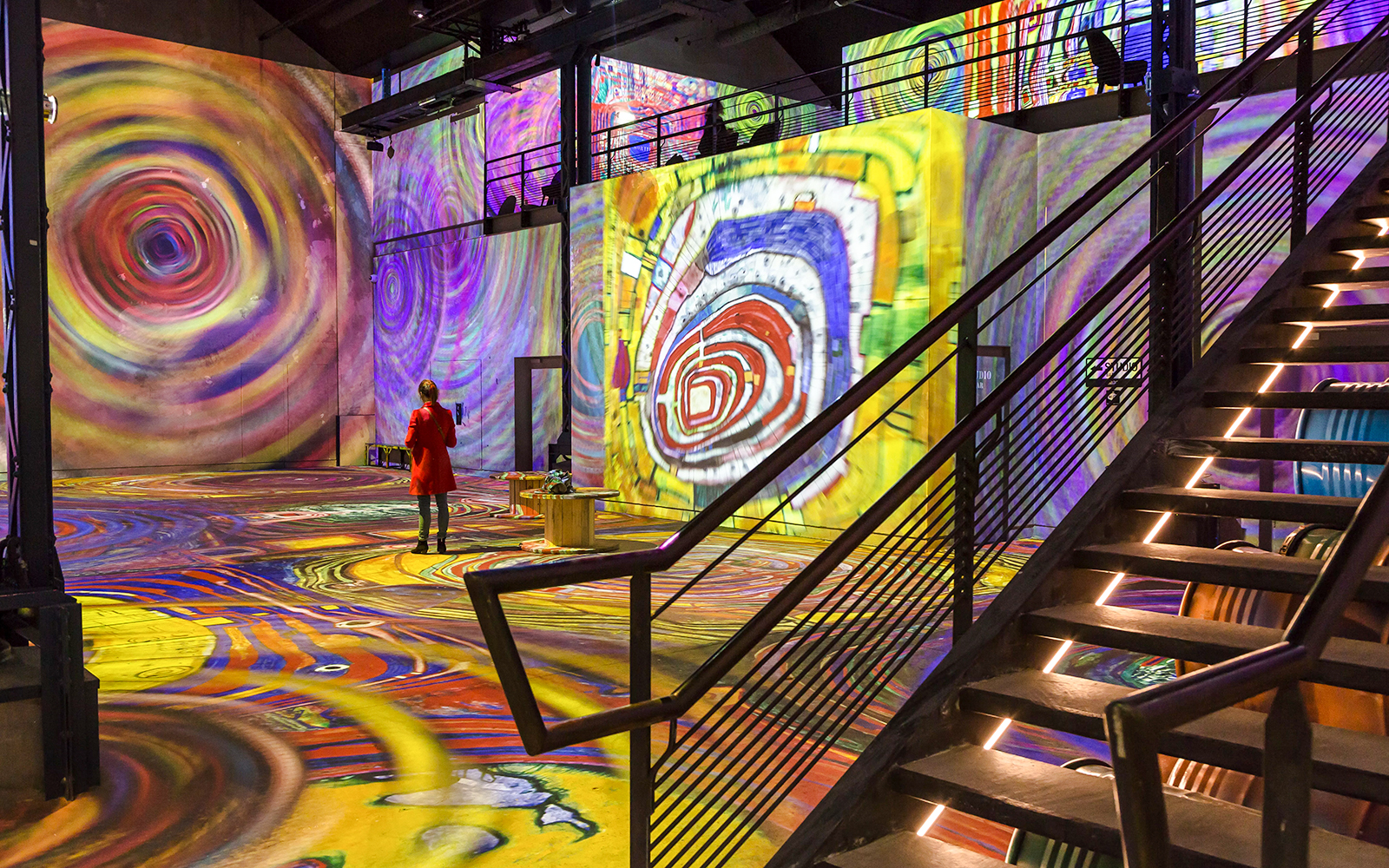Person viewing digital art projections at Atelier Des Lumières, Paris.