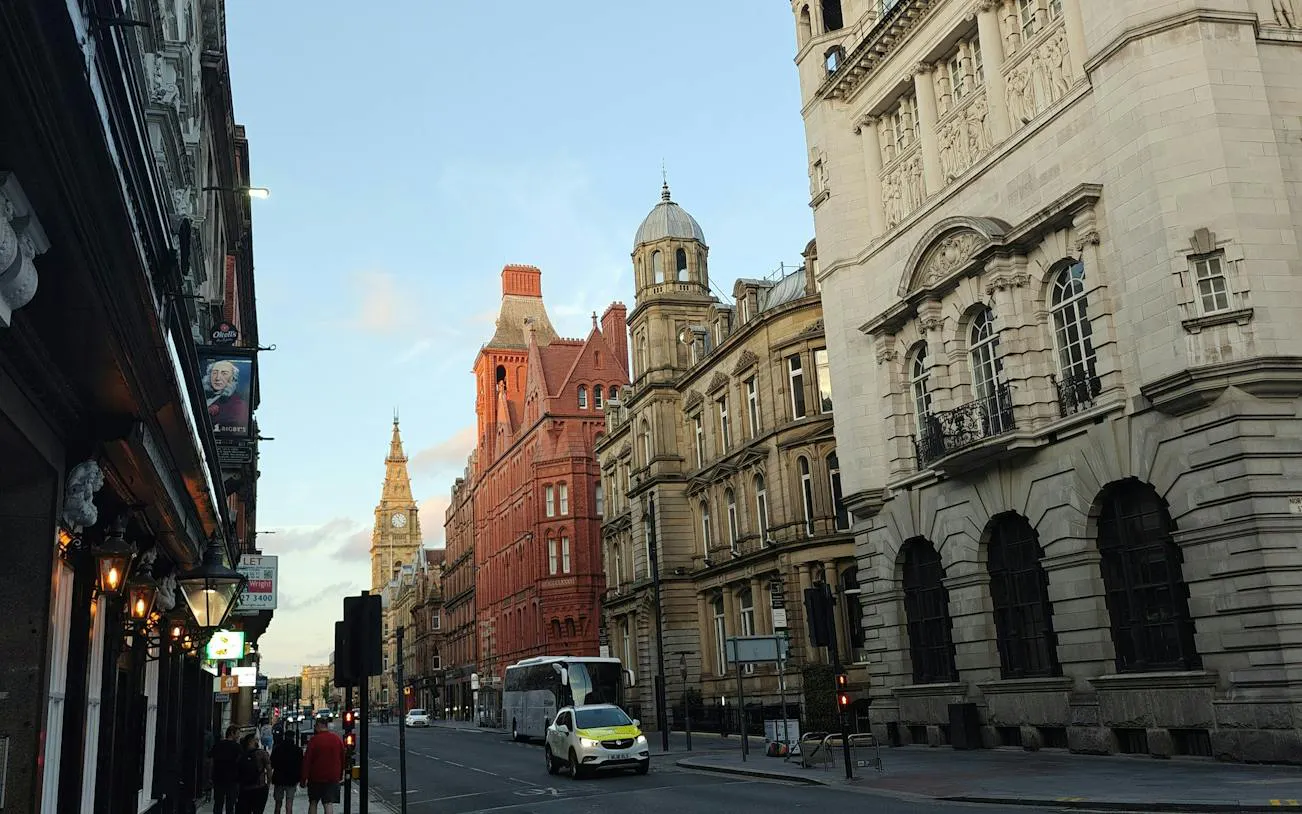 Street view of historic buildings in Liverpool, featuring a clock tower, part of the Murder Mystery city exploration game.