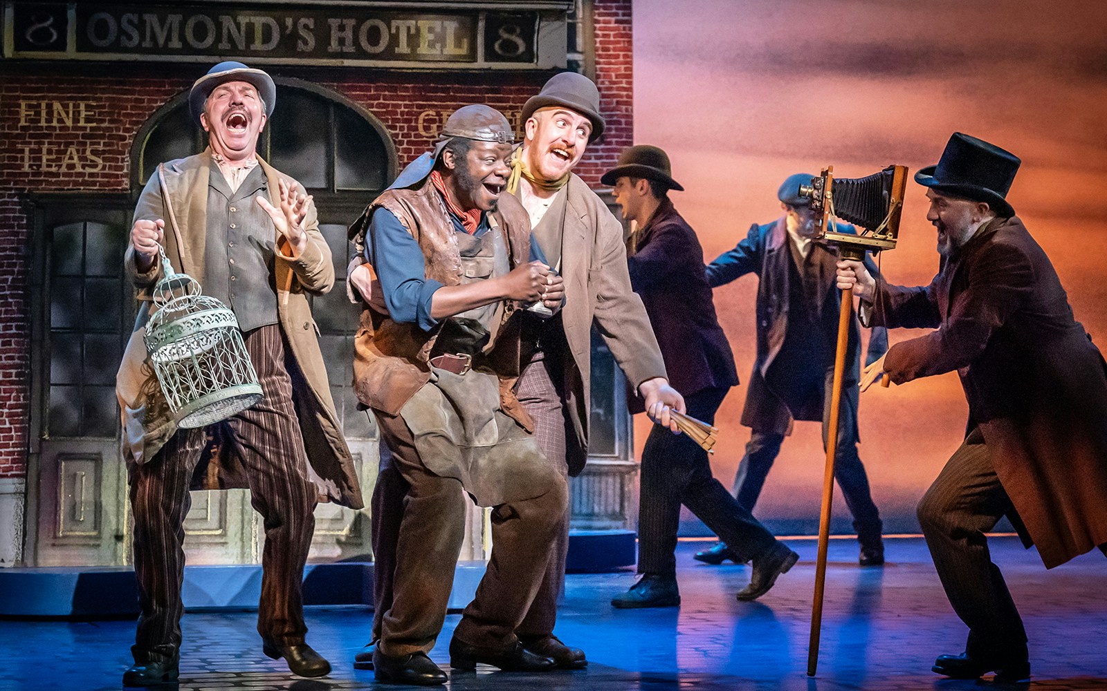 Actors performing a lively scene from "My Fair Lady" on stage.