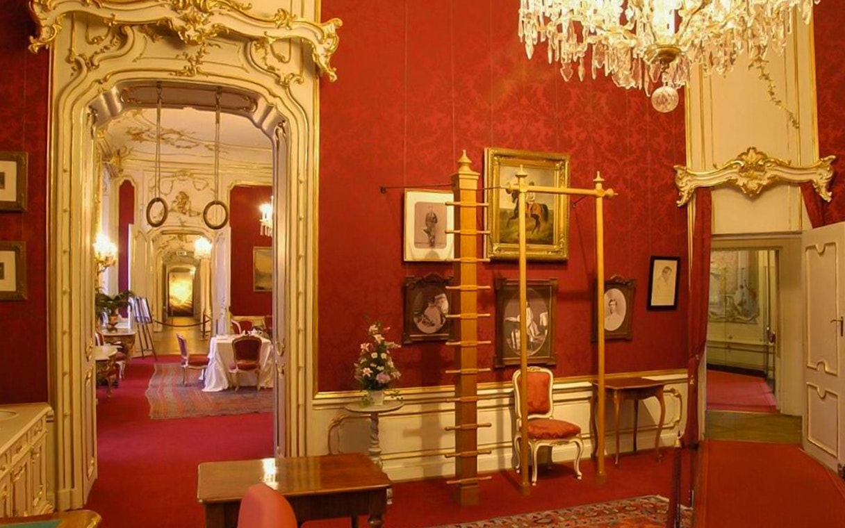 Interior of Imperial apartments at Sisi Museum with ornate decor and historical portraits.