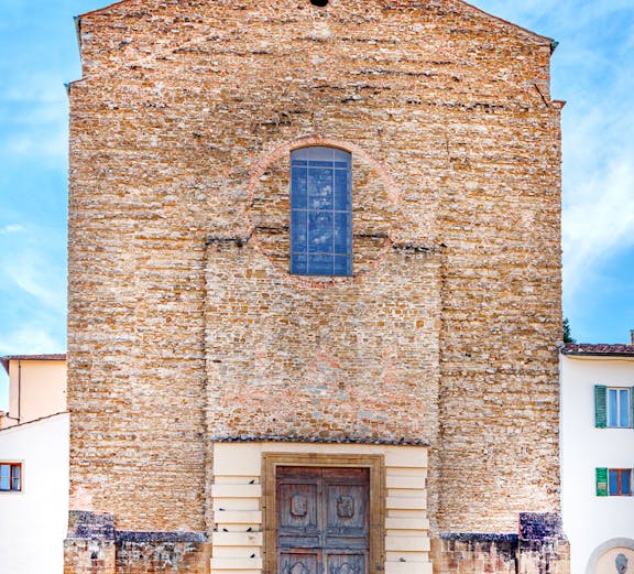 Facade of Brancacci Chapel in Florence with visitors sitting on steps.