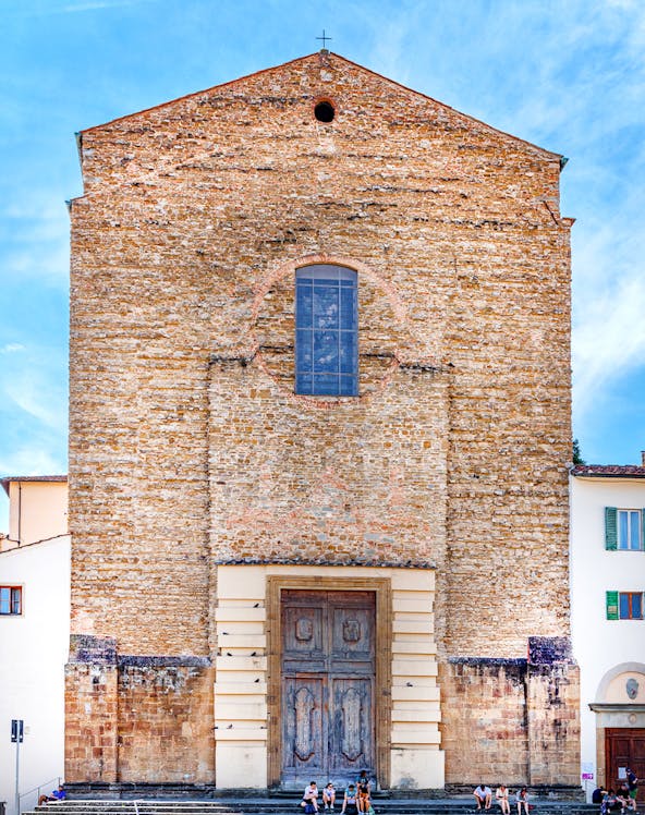 Facade of Brancacci Chapel in Florence with visitors sitting on steps.