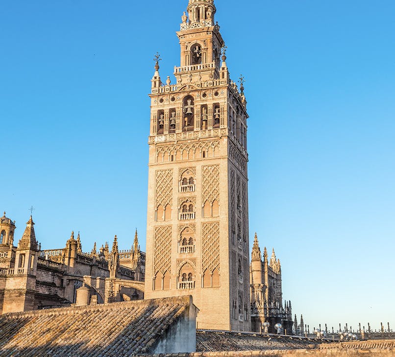La Giralda tower in Seville, Spain, with intricate architectural details against a clear sky.