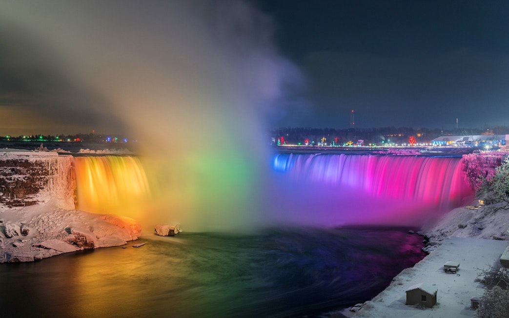 Niagara Falls illuminated with colorful lights in the evening.