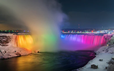 Niagara Falls illuminated with colorful lights in the evening.