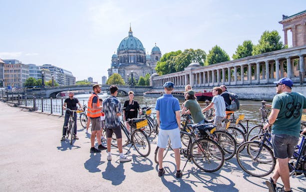 Group of cyclists on a guided tour near Berlin Cathedral along the Spree River.