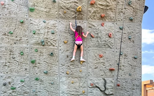 Child climbing rock wall at Hatta Wadi Hub adventure park.