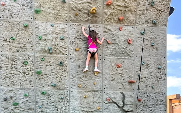 Child climbing rock wall at Hatta Wadi Hub adventure park.