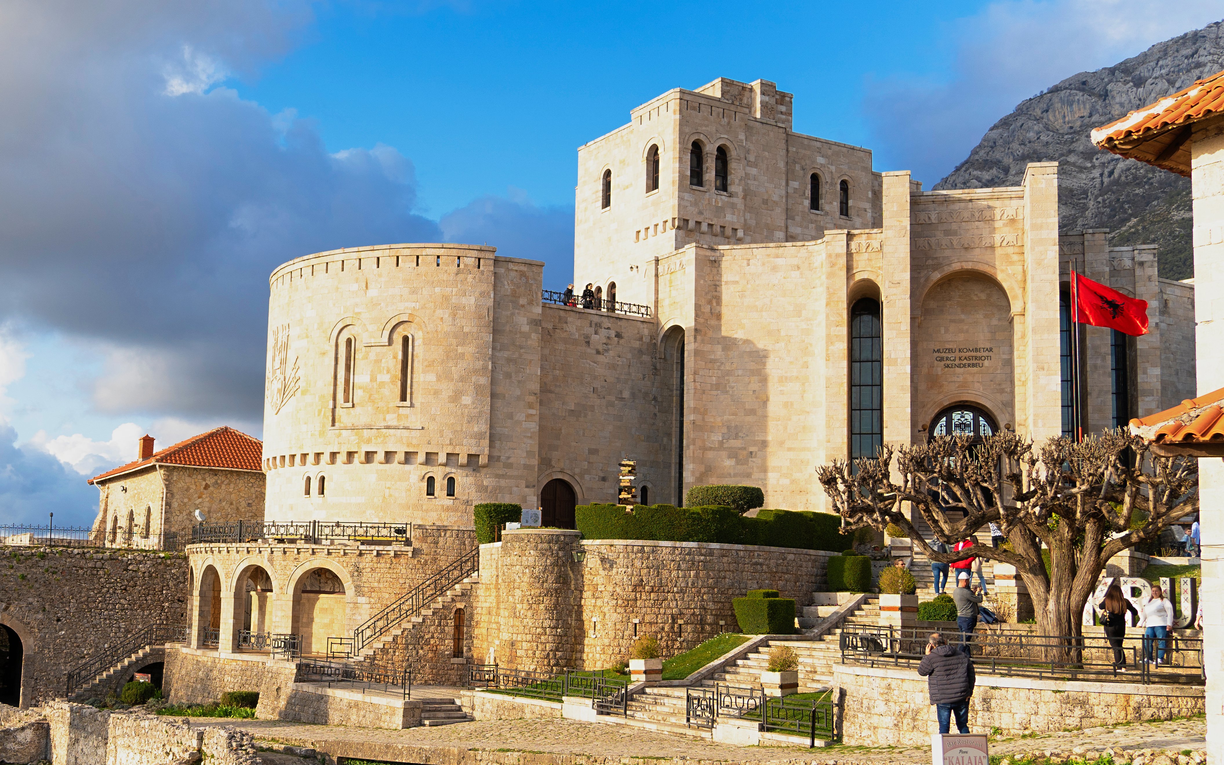 Kruja Castle exterior with stone walls and Albanian flag, Kruja, Albania.