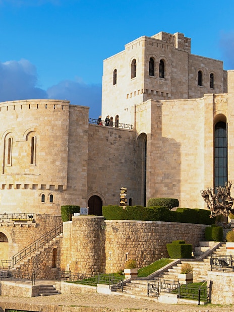 Kruja Castle exterior with stone walls and Albanian flag, Kruja, Albania.