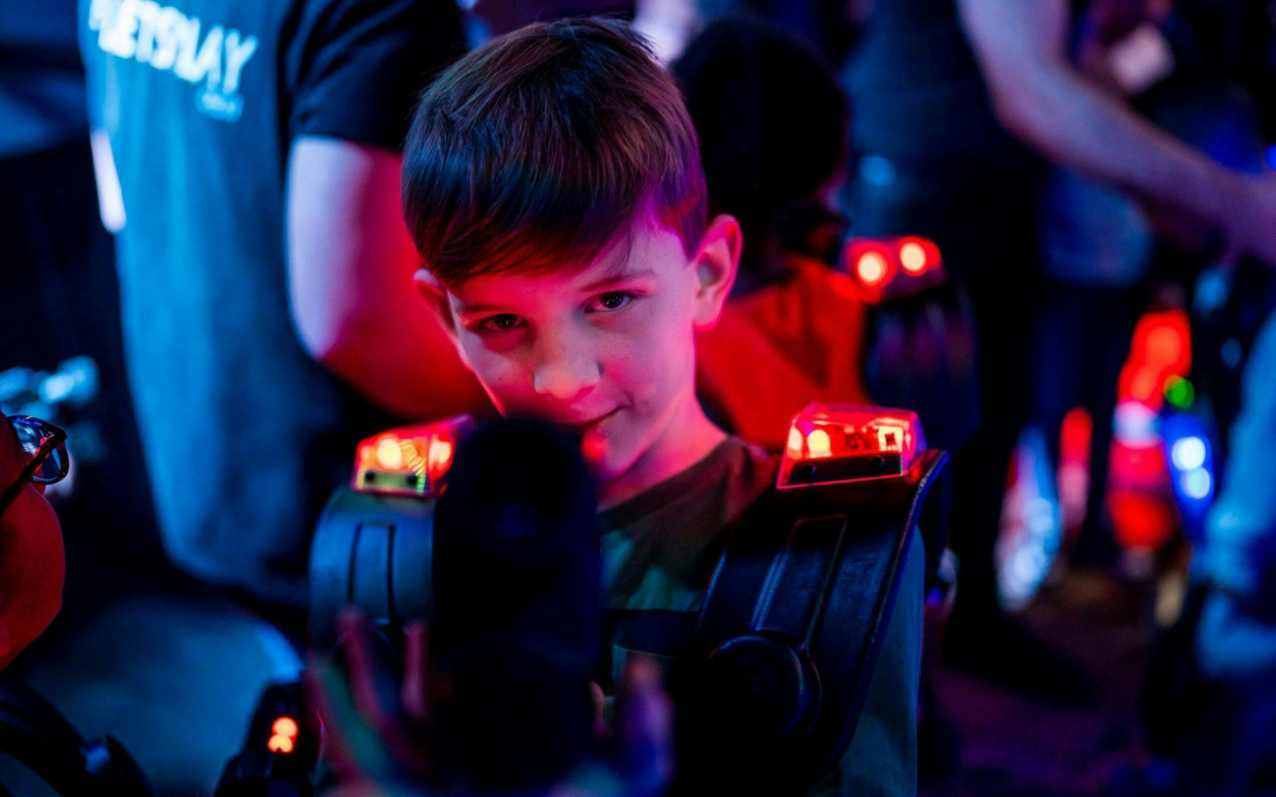 Child playing laser tag in Rotterdam with glowing gear.