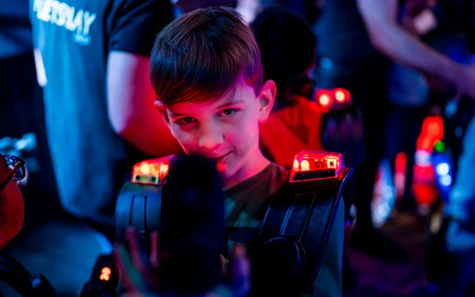 Child playing laser tag in Rotterdam with glowing gear.