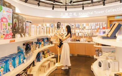Woman browsing merchandise at Shanghai Tower Collection gift shop.