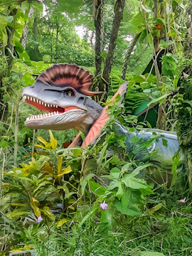 Dinosaur model in lush greenery at Dino Park Yanbaru Subtropical Forest.