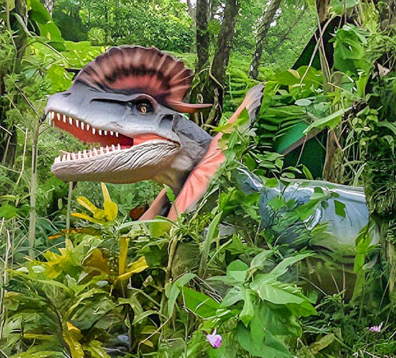 Dinosaur model in lush greenery at Dino Park Yanbaru Subtropical Forest.