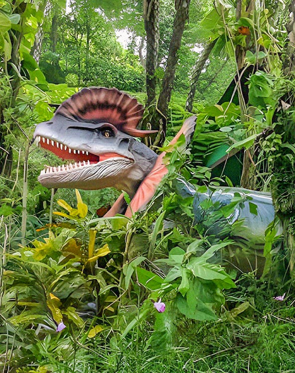 Dinosaur model in lush greenery at Dino Park Yanbaru Subtropical Forest.