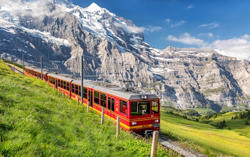 Train traveling through the scenic Jungfrau region in Switzerland with mountain backdrop.