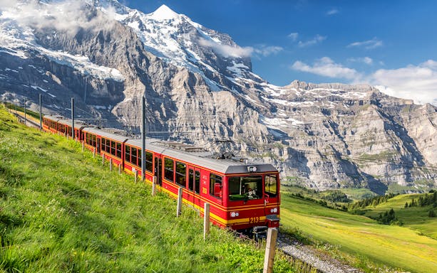 Train traveling through the scenic Jungfrau region in Switzerland with mountain backdrop.