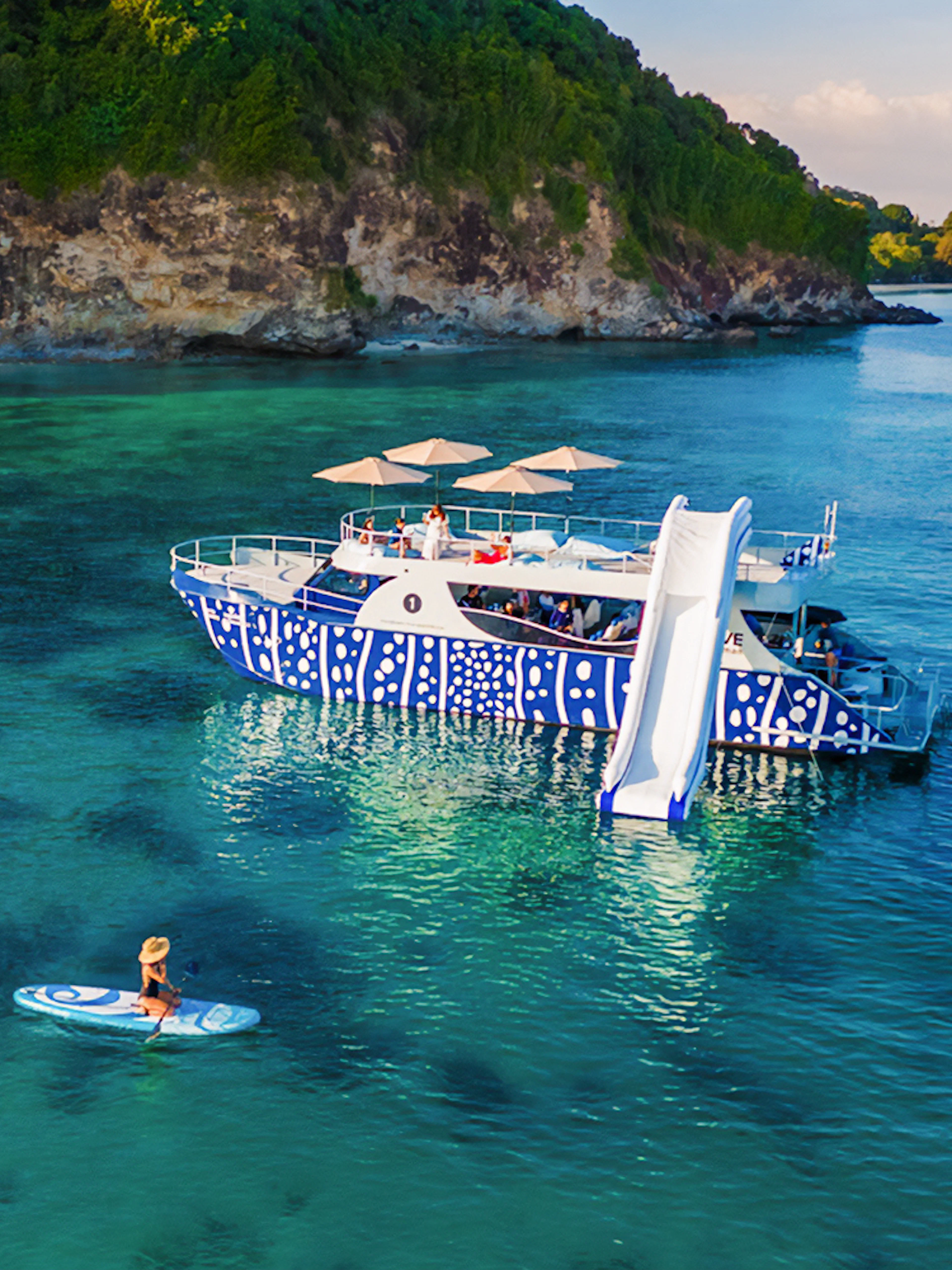 Tourist kayaking near whale shark fleet boat with slide in tropical waters.