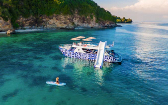 Tourist kayaking near whale shark fleet boat with slide in tropical waters.