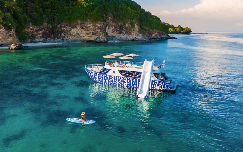 Tourist kayaking near whale shark fleet boat with slide in tropical waters.