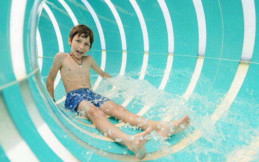 Child sliding in Jellyfish Twist water slide at Hurricane Harbor Arlington.