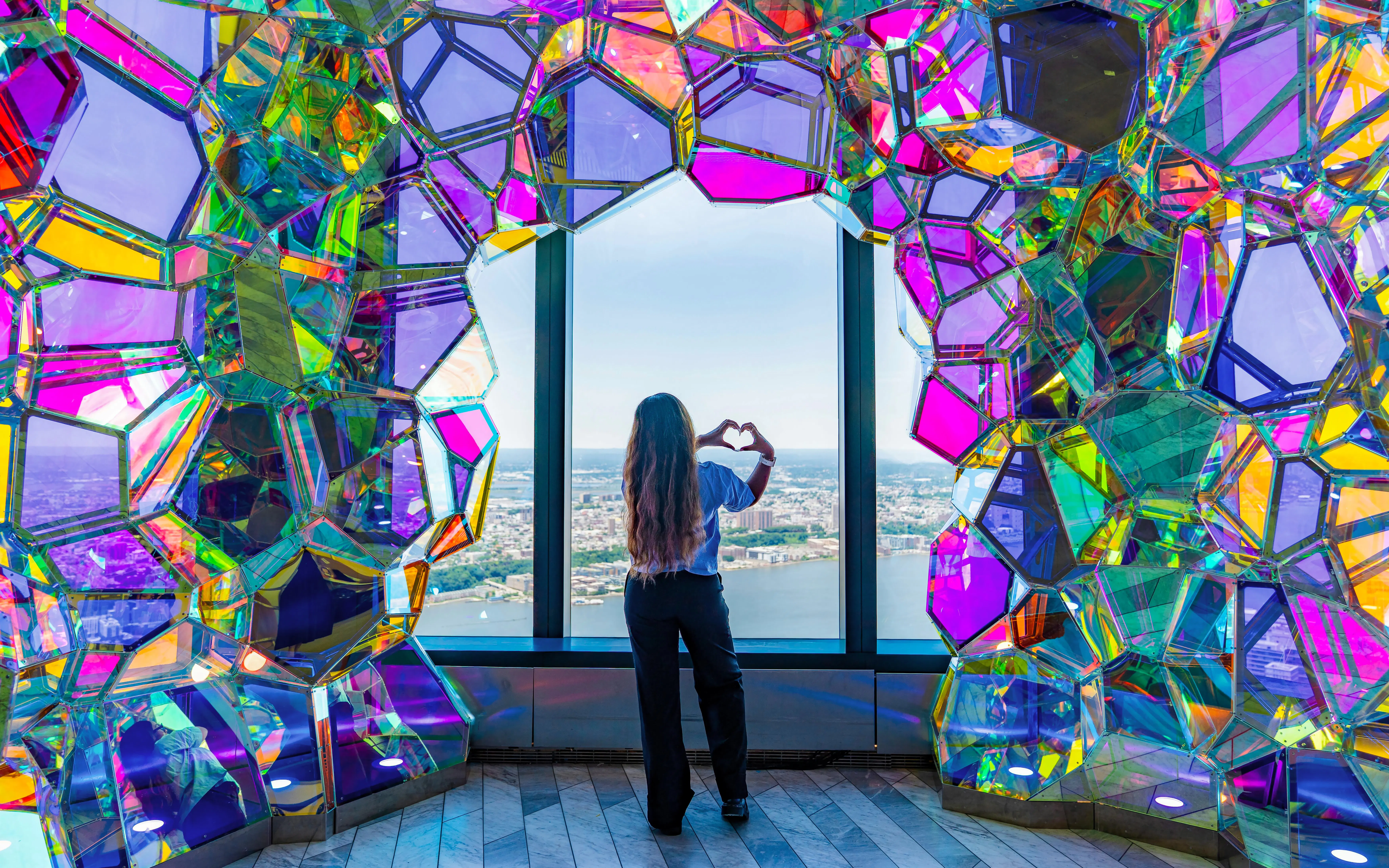 Person viewing New York skyline through colorful glass at Edge Observatory.