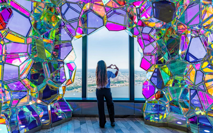 Person viewing New York skyline through colorful glass at Edge Observatory.