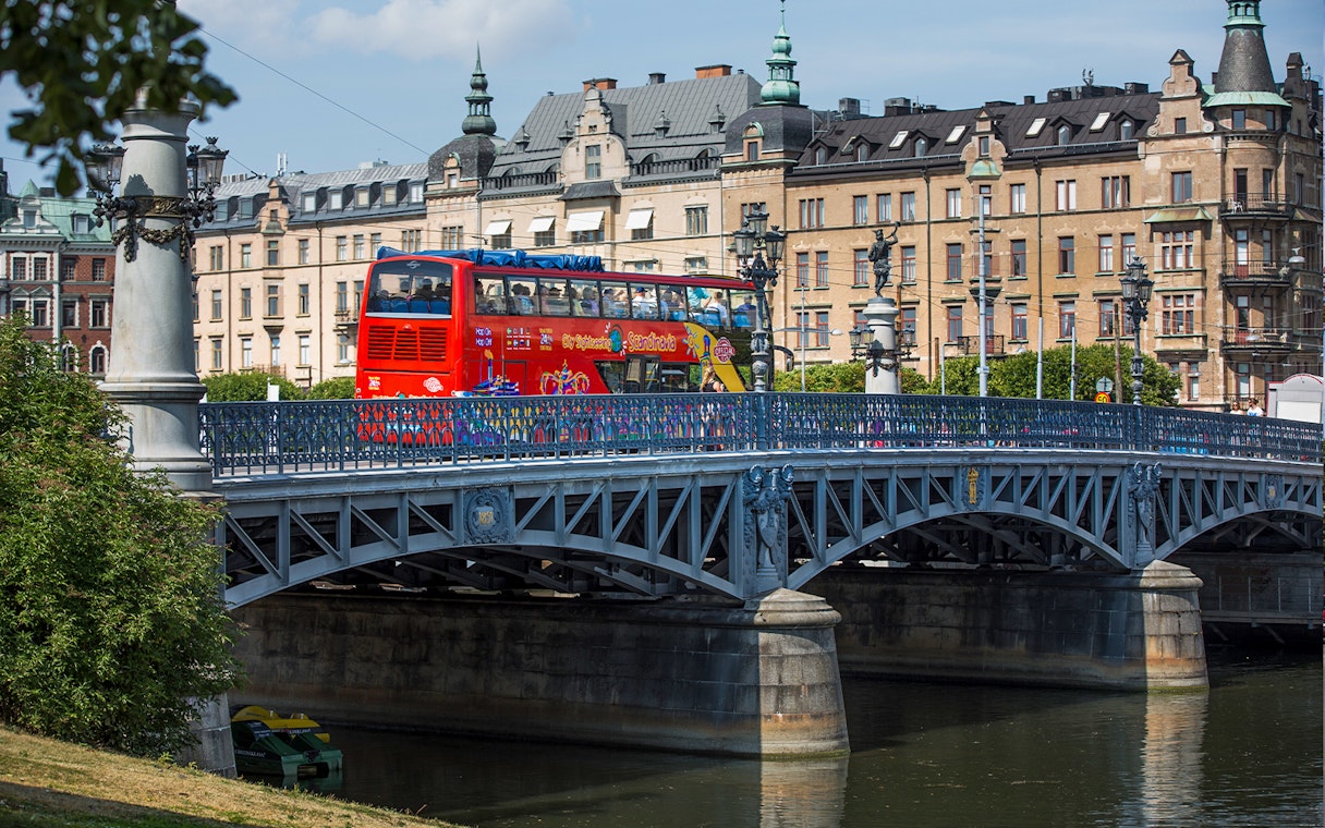 Red double-decker bus on a bridge in Stockholm during a Hop-On-Hop-Off tour.