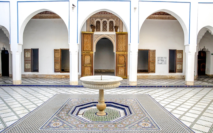 Bahia Palace courtyard with ornate fountain and arches in Marrakech, Morocco.
