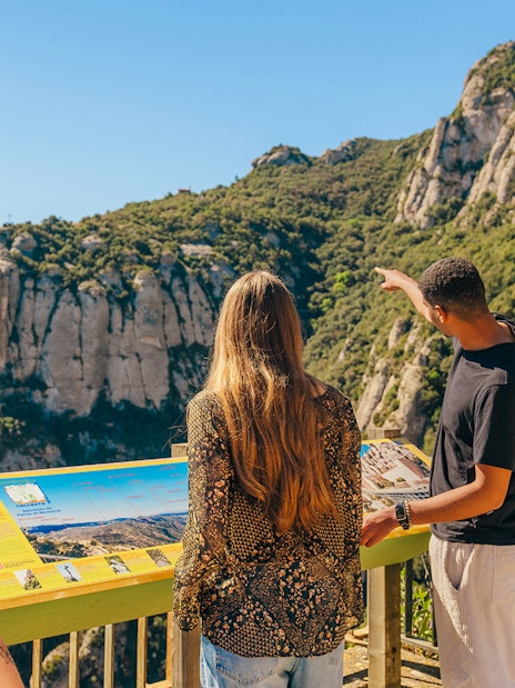 Tourists viewing Montserrat Monastery mountain landscape from observation point.