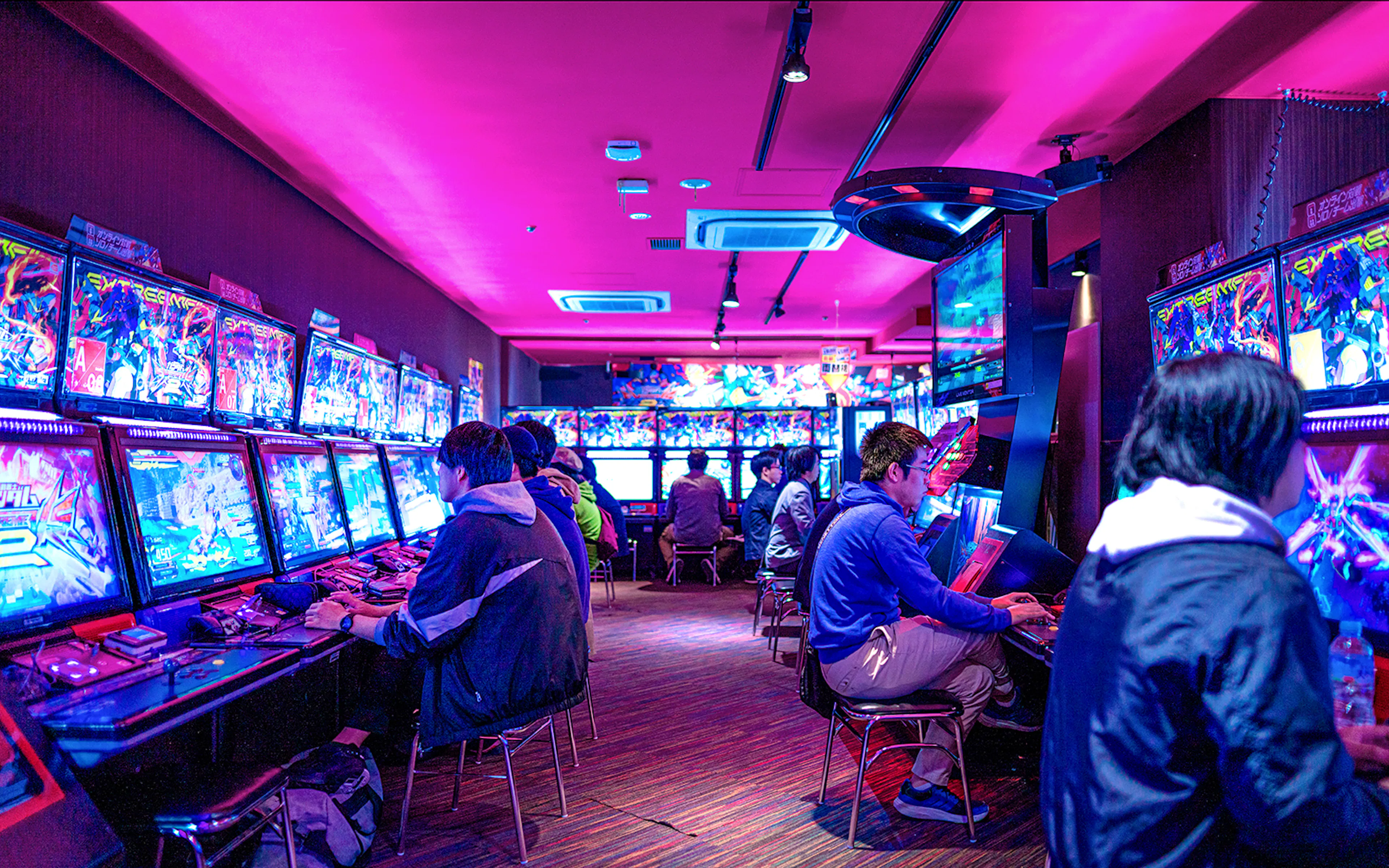 People playing arcade games in Akihabara gaming center during retro gaming tour.
