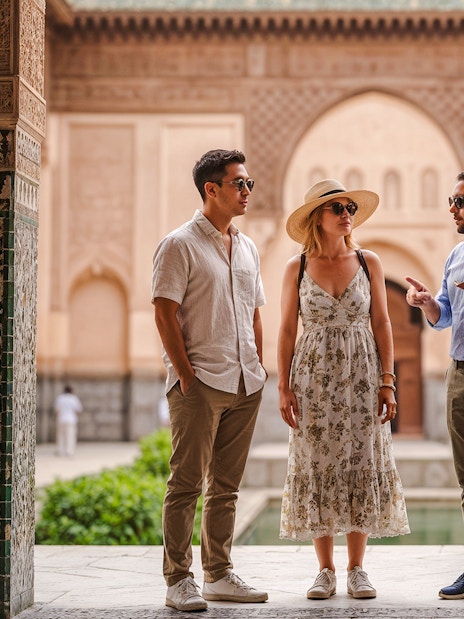Tour guide explaining architecture to visitors at Ben Youssef Madrasa, Marrakech.