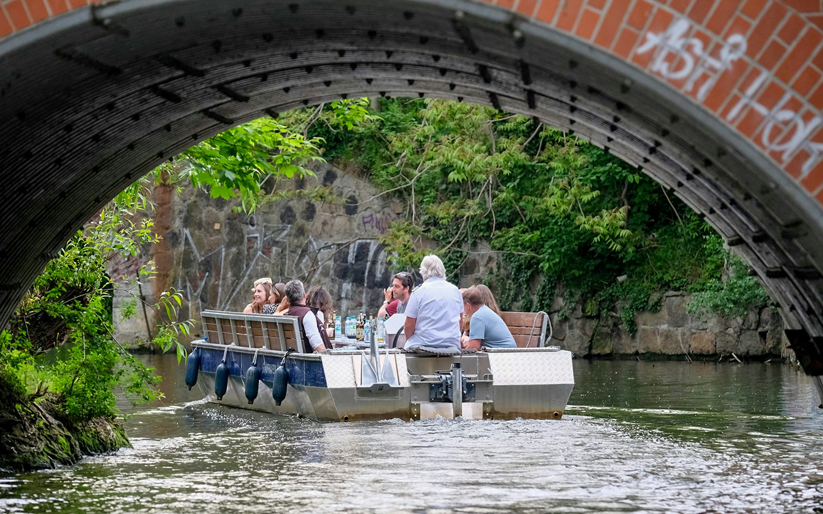 Guests navigating Karl Heine Canal in Leipzig on a motorboat tour.