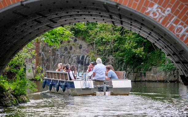 Guests on a motorboat tour under a bridge on Karl Heine Canal, Leipzig.