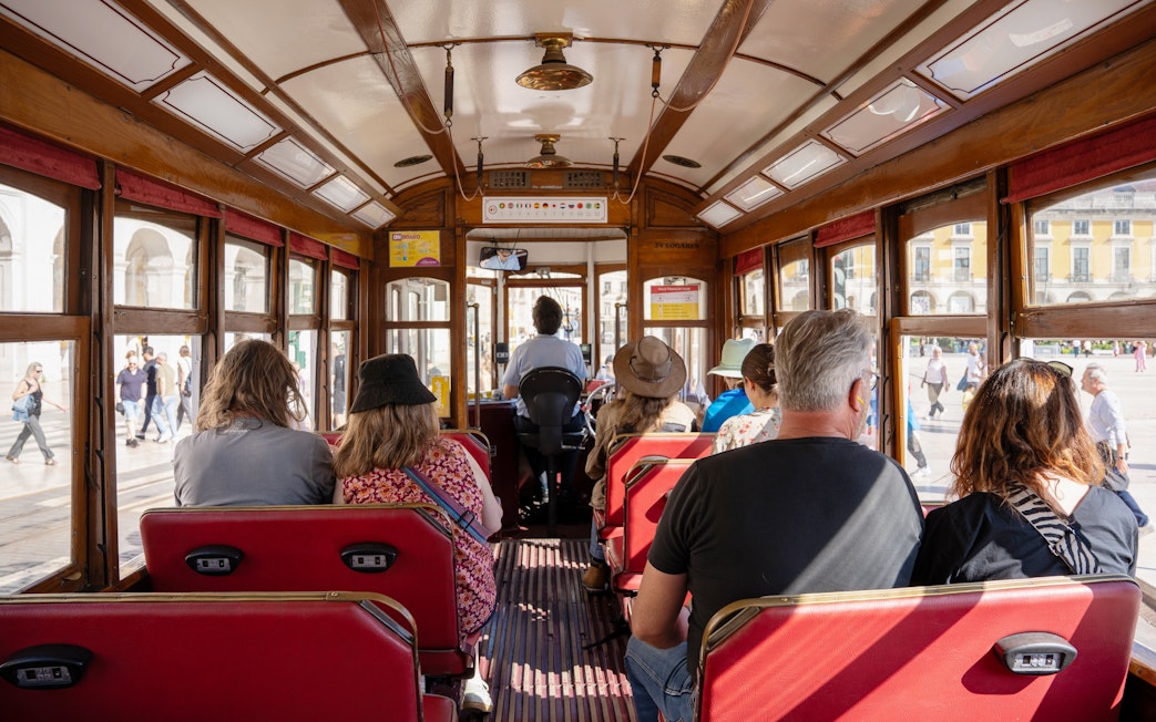 Tourists seated inside a vintage tram during Lisbon Hop-on Hop-off Bus Tour.