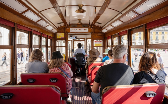 Tourists seated inside a vintage tram during Lisbon Hop-on Hop-off Bus Tour.
