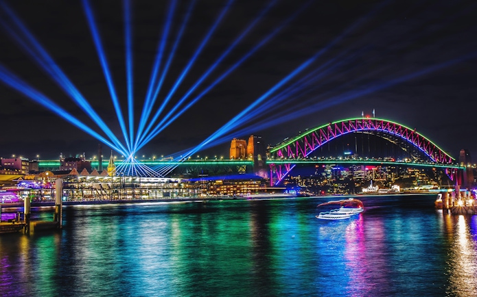 Sydney Harbour Bridge illuminated during Vivid Sydney, viewed from a tall ship dinner cruise.