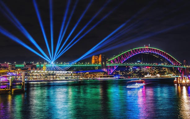 Sydney Harbour Bridge illuminated during Vivid Sydney, viewed from a tall ship dinner cruise.