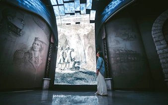 Visitor admiring historical Niagara Falls mural at Niagara Takes Flight, Canada.