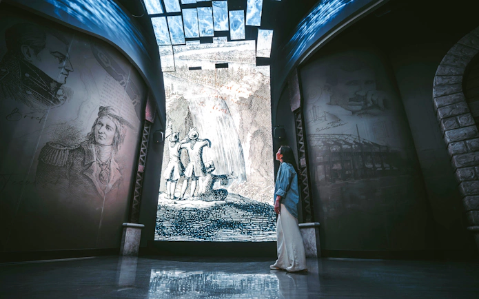Visitor admiring historical Niagara Falls mural at Niagara Takes Flight, Canada.