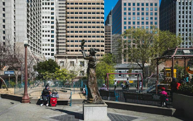 Statue in San Francisco park with skyscrapers in background, part of Chinatown exploration game.