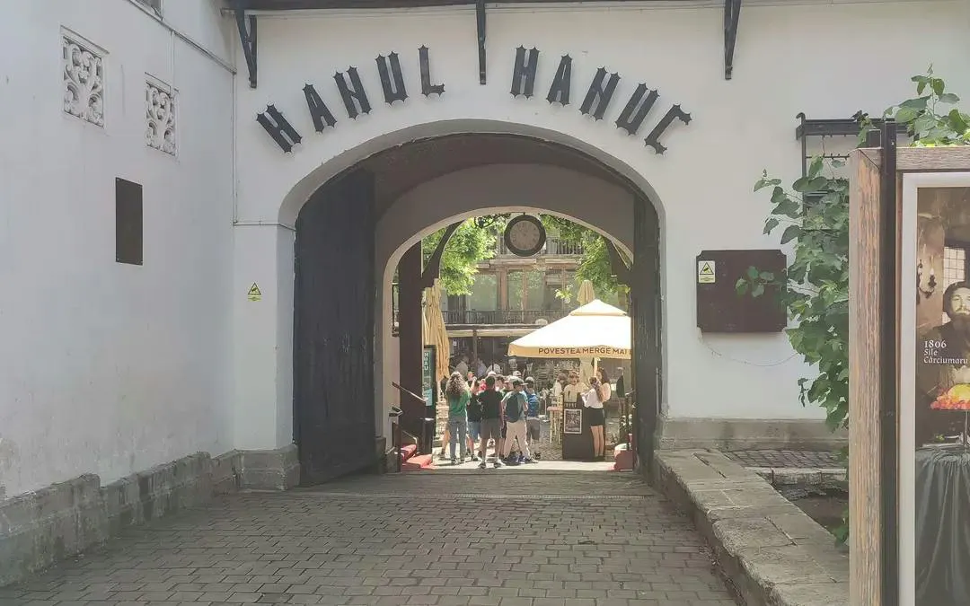 Entrance to Hanul Manuc courtyard, Bucharest, with visitors exploring the historic site.