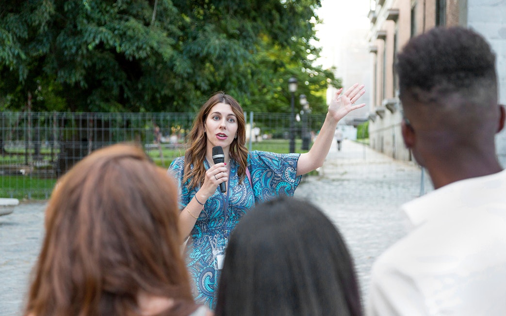 Tour guide speaking to tourists in a park setting.