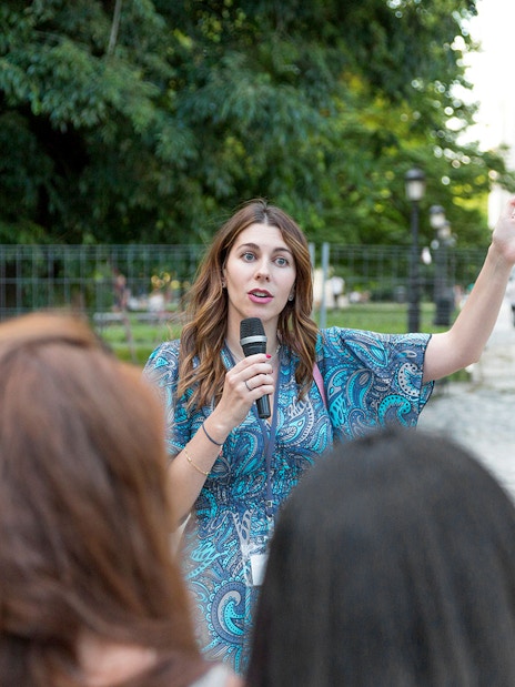 Tour guide speaking to tourists in a park setting.