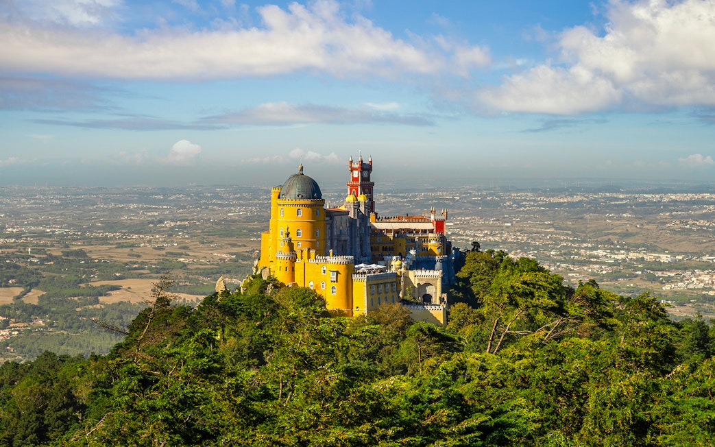 Pena Palace in Sintra, Portugal, surrounded by lush greenery with a panoramic view.