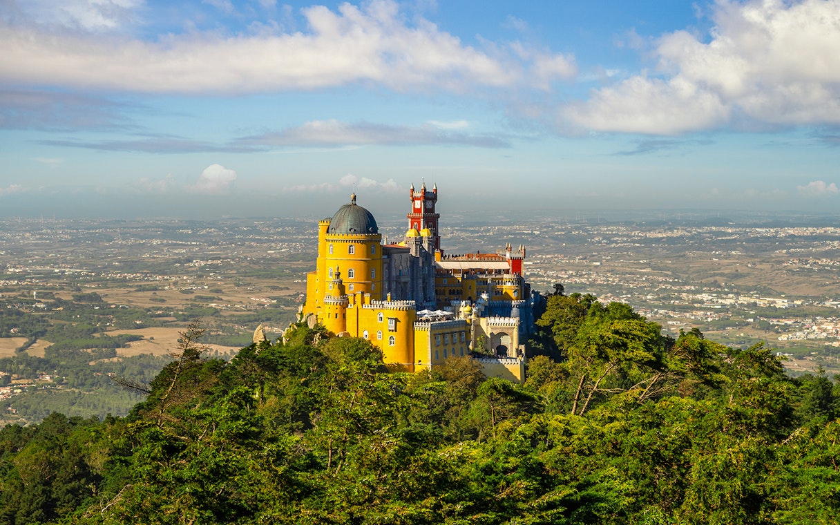 Pena Palace in Sintra, Portugal, surrounded by lush greenery with a panoramic view.